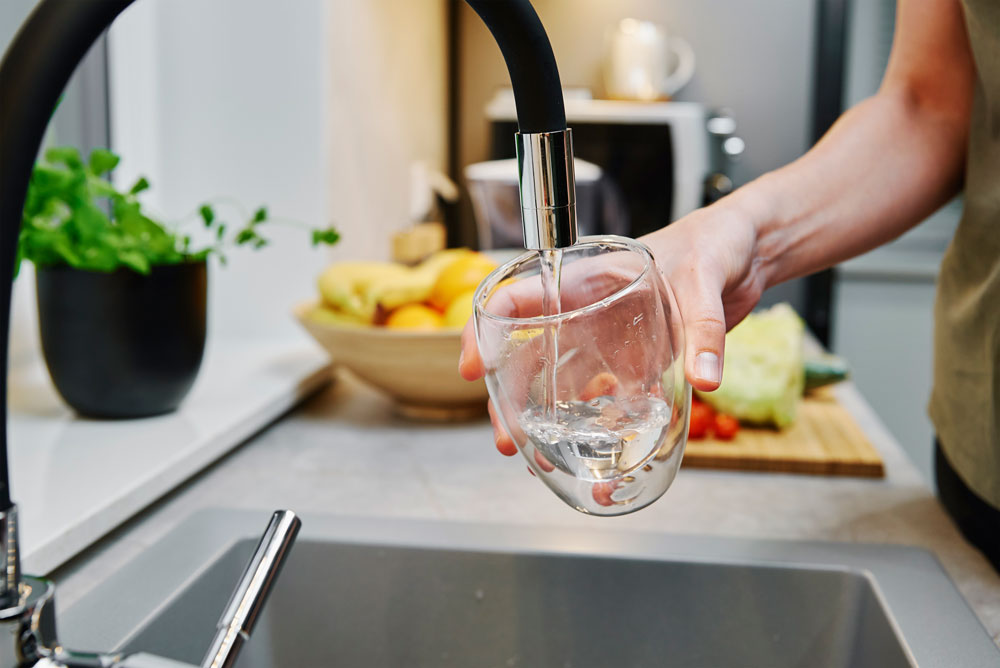 woman filling glass of water from the sink